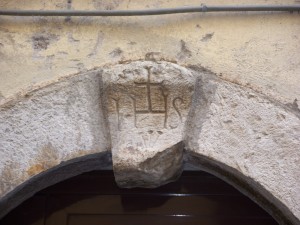 Chiave di volta di palazzo di corso Italia con Trigramma di Cristo e Chiodi della Crocifissione